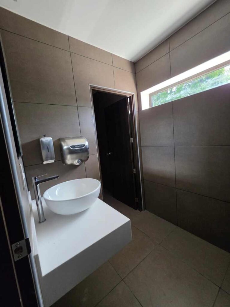 Baño con lavamanos de sobreponer y acabados en porcelanato