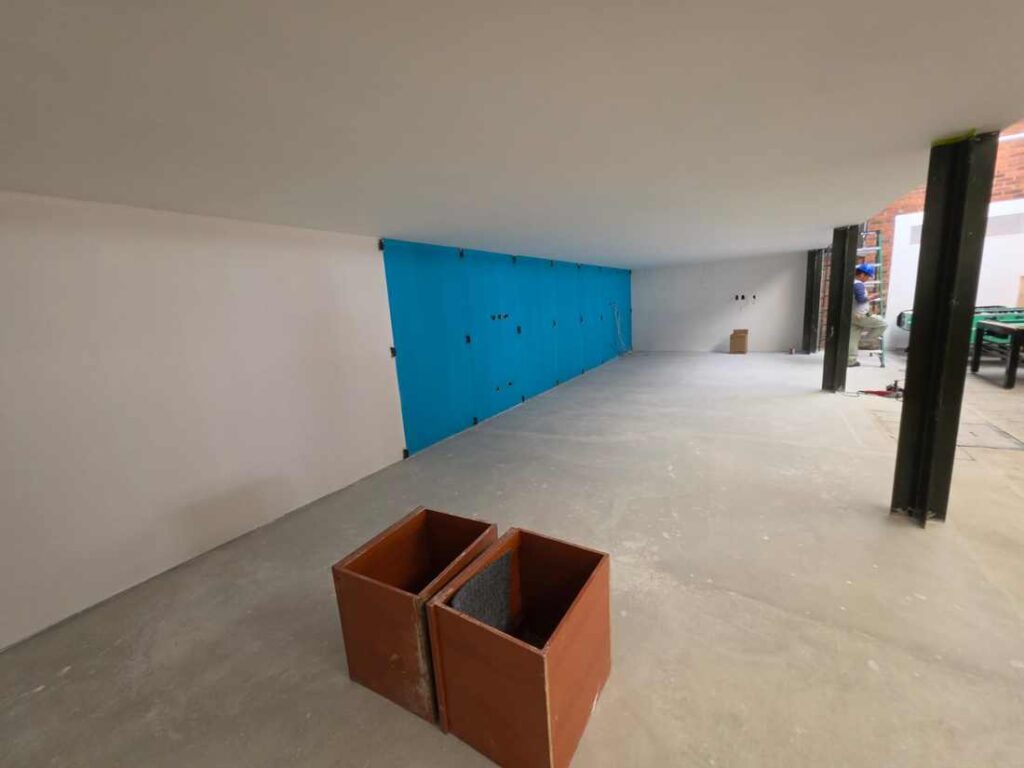 Espacio en proceso de obra con muro azul y piso de concreto
