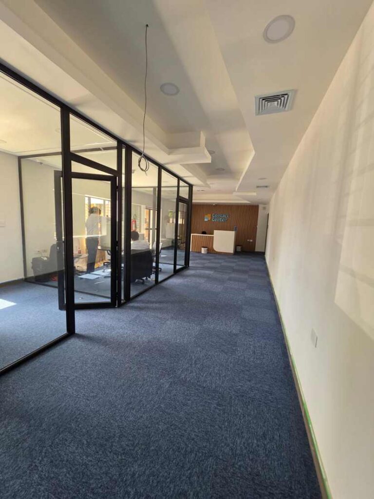 Pasillo con divisiones de vidrio hacia la recepción Contact Center