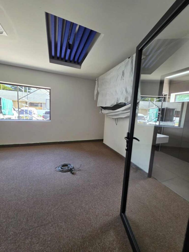 Sala con alfombra y detalle de lamas acústicas en cielo